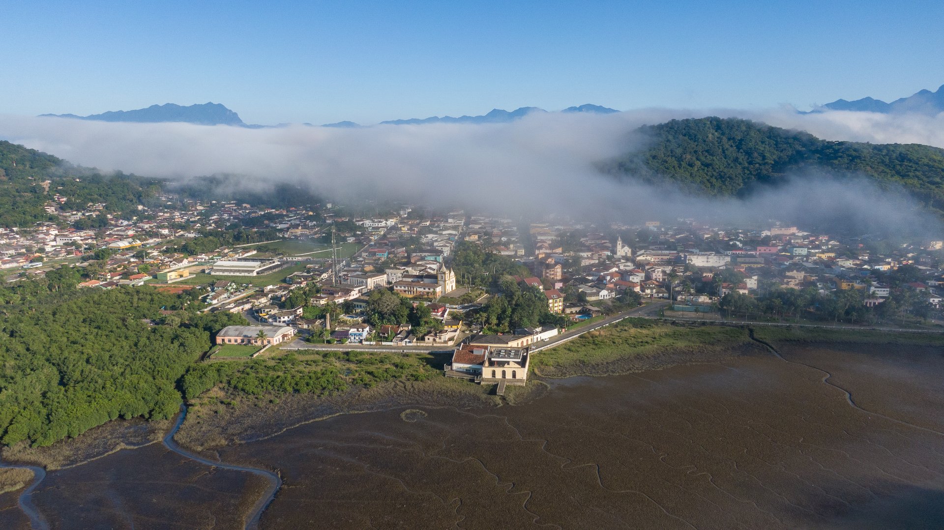 Litoral visto de cima — mar, pedras e floresta